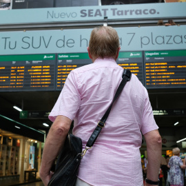 31/07/2019 - Un viajero espera frente a uno de los paneles de Salidas y Llegadas de la estación de trenes de Atocha