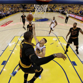 Stephen Curry (c) lucha por el balón con LeBron James en el quinto partido de la final.