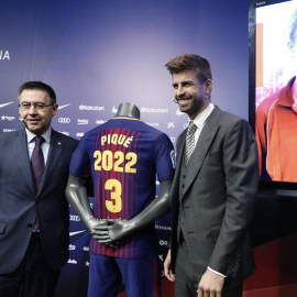 Piqué posa con el presidente del Barcelona, Josep María Bartomeu, tras ampliar su contrato. / ANDREU DALMAU (EFE)