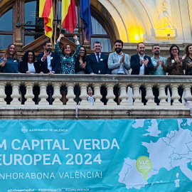 Parte de la corporación municipal de València saluda desde el balcón del Ayuntamiento con un cartel donde indica que la ciudad será la Capital Europea Verde 2024.