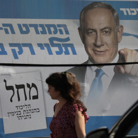 Una mujer pasa junto a una valla publicitaria del ex primer ministro israelí y líder del partido Likud, Benjamin Netanyahu, en Jerusalén, Israel.