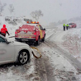 Los bomberos trasladan a un coche durante una nevada. EFE