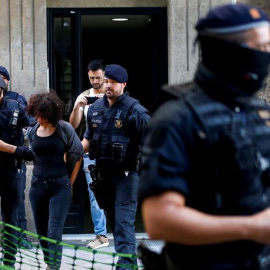 Mossos d'Esquadra trasladan a una persona detenida tras un operativo conjunto con la Guardia Urbana para desmantelar pisos convertidos en puntos de venta de droga en el barrio de Sant Antoni de L'Eixample y en el distrito de Sants-Montjuïc 