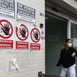 Una sanitaria con mascarilla en la puerta del Centro de Salud Ángela Uriarte, donde hay carteles de protesta que rezan 'Urgencias Cerradas, tu salud vendida', a 21 de octubre de 2022, en Madrid.