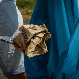 Un hombre tira un envoltorio de comida a la basura.