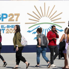 Varias personas caminan junto al cartel de la COP27 en Sharm El Sheikh, Egipto.