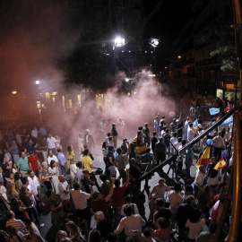 Varias personas disfrazados de presos lanzan botes de humo en los alrededores de la calle Génova de Madrid./ EFE