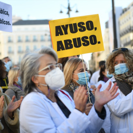 Un grupo de personas con un cartel donde se puede "Ayuso, abuso" en una concentración en defensa de la Atención Primaria, a 13 de noviembre de 2021, en Madrid, (España).