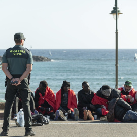 Un agente de la Guardia Civil custodia a un grupo de personas migrantes llegadas en patera a la costa de Teguise, en Lanzarote, a 26 de diciembre de 2023.