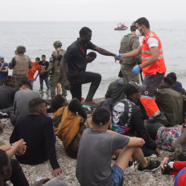 Miembros del Ejército de Tierra y de la Cruz Roja, junto a un grupo de migrantes que han logrado cruzar uno de los espigones fronterizos de Ceuta.