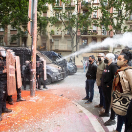 Policías antidisturbios de los Mossos d'Esquadra frente a las personas conventradas para evitar el desalojo del edificio conocido como Bloc Llavors, en el barrio del Poble Sec de Barcelona, que han lanzando objetos y pintura contra la línea