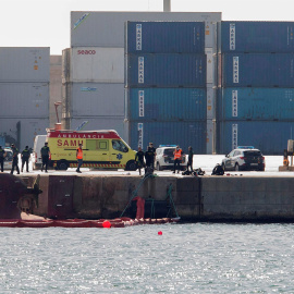 Efectivos de la Guardia Civil y del servicio de emergencias esperan en el Muelle del Centenario de Port Castelló durante las tareas de búsqueda de dos personas desaparecidas tras el vuelco del buque "Nazmuye Ana" (a la izquierda, en la imag