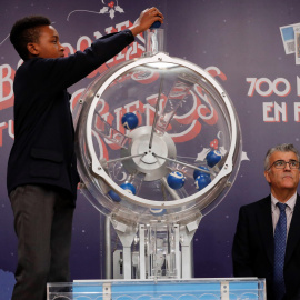 Uno de los niños de San Ildefonso intruduce las bolas en el bombo para el sorteo de la lotería de El Niño. EFE/ Zipi