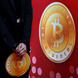 Un empleado de la tienda bitcoin de Hong Kong sostiene el logo de la moneda virtual. REUTERS/Bobby Yip