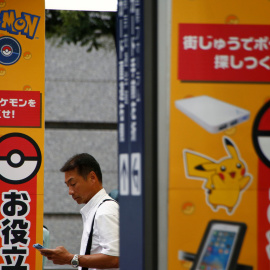 Un hombre utiliza su teléfono móvil enfrente de un anuncio con la imagen del juego Pokémon GO en una tienda de Tokio, Japón. REUTERS/Kim Kyung-Hoon