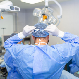 Vista trasera del cirujano masculino con mascarilla quirúrgica en el quirófano del hospital