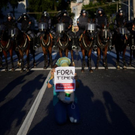 Policías brasileños y un manifestante con una pancarta en la que se reza "Fuera Temer", durante una protesta contra los Juegos Olímpicos. EFE/FAVIO TEIXEIRA