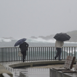 Dos personas caminan con un paraguas al lado de la playa del Orzán, a 22 de enero de 2024, en A Coruña.