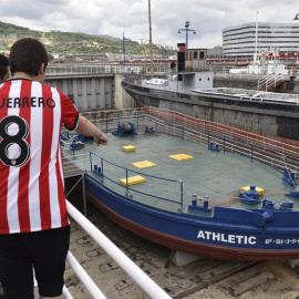 Dos jóvenes observan la legendaria gabarra con la que el Athletic Club celebró sus títulos en 1983 y 1984. EFE/ Miguel Toña