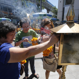 Turistas malasios queman incienso ante el altar del templo de Erawan donde el pasado lunes estalló una bomba en Bangkok.- EFE