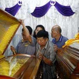 Un herido en el atentado del lunes en Bangkok, junto a los ataúdes de su esposa e hijo, muertos en la explosión.- REUTERS / Olivia Harris