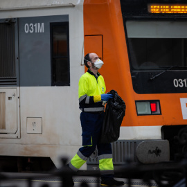 Un trabajador de la limpieza trabaja protegido con una mascarilla junto a un tren en Barcelona/Catalunya (España)