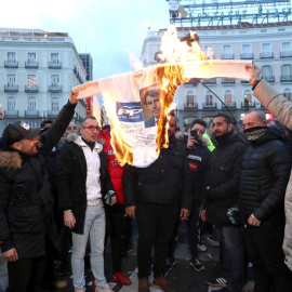 Los taxistas queman un cartel del PP con la cara del presidente de la Comunidad de Madrid en  segundo día consecutivo en la madrileña Puerta del Sol. (KIKO HUESCA | EFE)