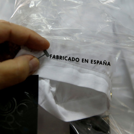 Un trabajador sostiene una etiqueta que pone 'Hecho en España' en una camisa en una fábrica textil en Madrid. REUTERS/Andrea Comas