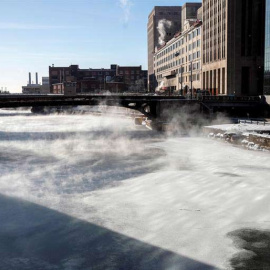 Varias personas cruzan un puente mientras la niebla se eleva desde el río Chicago. (KAMIL KRZACZYNSKI | EFE)