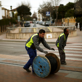 Dos trabajadores trasladan un rodillo de cable eléctrico en la localidad malagueña de Ronda. REUTERS / Jon Nazca