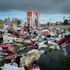 Personas recolectan láminas de metal de un supermercado dañado para reconstruir sus casas destruidas por el ciclón Idai en Beira, Mozambique | AFP/ Yasuyoshi Chiba