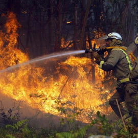 Los bomberos apagan uno de los numerosos focos del incendio en la localidad coruñesa de Rianxo. (LAVANDEIRA JR. | EFE)