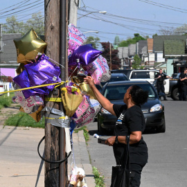  Una mujer deja un globo en un monumento improvisado cerca de una tienda Tops Grocery en Buffalo, Nueva York, el 15 de mayo de 2022, el día después de que un hombre armado matara a tiros a 10 personas. Los residentes afligidos de la ciudad 