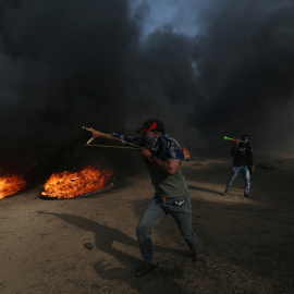 Un manifestante usa un tirachinas para arrojar piedras durante una protesta en la que los palestinos reclaman el derecho a regresar a su patria, en la frontera entre Israel y Gaza. REUTERS / Ibraheem Abu Mustafa