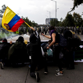 21/11/2019.- Un grupo de jóvenes se cubre frente a miembros de la Policía durante una manifestación en Bogotá (Colombia). / EFE - JUAN ZARAMA