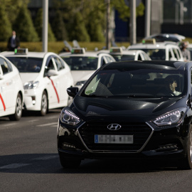 Un coche VTC pasando junto a una hilera de taxis en el centro de Madrid. / Europa Press