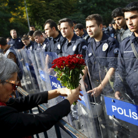 Una manifestante muestra un ramo de flores en la barricada policial deslpegada frente a la concentración en recuerdo de las víctimas del doble atentado suicida en Ankara. REUTERS/Umit Bektas