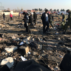 Miembros del equipo de rescate con personas revisan los escombros de un accidente aéreo perteneciente a Ukraine International Airlines después del despegue del aeropuerto iraní Imam Khomeini, en las afueras de Teherán, Irán, 8 de enero de 2