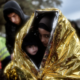 Los niños intentan entrar en calor con mantas de emergencia mientras llegan otros refugiados e inmigrantes a la isla griega de Lesbos. AFP / ARIS MESSINIS