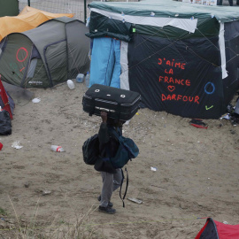 Un grupo de refugiados, junto a una pintada que dice "Amo Francia", en la 'Jungla' de Calais durante la evacuación del campo. REUTERS/Pascal Rossignol