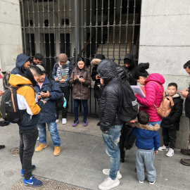 Varios solicitantes de asilo intentan reservar su cita previa de extranjería para acceder al sistema de acogida, en la puerta del Samur Social de Madrid.- RSP