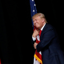 El candidato republicano a la presidencia de Estados Unidos, Donald Trump, abraza una bandera nacional durante un mítin en Tampa, Florida. REUTERS/Jonathan Ernst