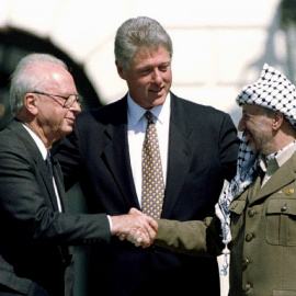 El presidente de EEUU, Bill Clinton, observa mientras el primer ministro israelí Isaac Rabin y el líder de la Organización de Liberación de Palestina (OLP),  Yasser Arafat, se dan la mano después de la firma de del acuerdo de paz en la Casa