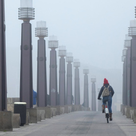 13/01/2020.- Una joven atraviesa en bicicleta el Puente de Piedra sobre el río Ebro a su paso por Zaragoza este lunes. / EFE - JAVIER CEBOLLADA