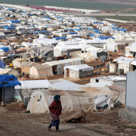 Una mujer siria desplazada camina por el campamento Atmah IDP, ubicado cerca de la frontera con Turquía, Siria. -Reuters