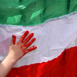 Una mujer usa pintura roja en una bandera iraní durante una protestan frente a la sede local de las Naciones Unidas en solidaridad con el pueblo iraní, en Santiago, Chile, a 11 de noviembre de 2022. -Reuters / Ivan Alvarado