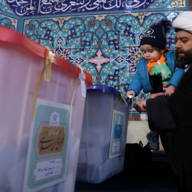 Un hombre y un niño junto a las urnas electorales durante las elecciones en Irán.- REUTERS