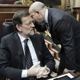 Mariano Rajoy escucha una confidencia del entonces ministro de Educación, José Ignacio Wert, en un debate de Presupuestos en el Congreso de los Diputados. EFE