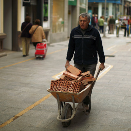 Un trabajador acarrea una carretilla con ladrillos en Ronda (Málaga). REUTERS