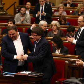 El presidente de la Generalitat, Carles Puigdemont (c), felicita al vicepresidente y conseller de Economía, Oriol Junqueras (i) el pasado día 20 en el Parlament. /EFE